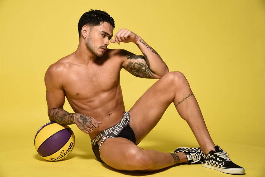 Dormir desnudo enseñanza - Hombre en ropa interior negra posando con balón de baloncesto sobre fondo amarillo
