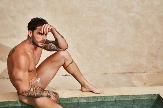 Entrenamiento para reducir abdomen - Hombre en ropa interior color piel sentado junto a una piscina