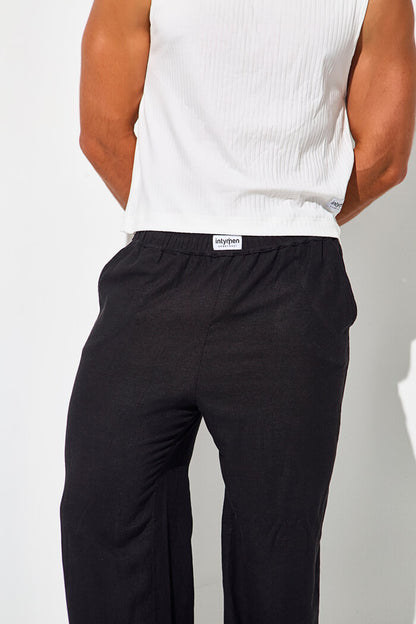 Pantalon pants hombre relajado 3d negro delantero - Vista trasera de pantalón negro tipo pijama con pretina elástica y camiseta sin mangas blanca.