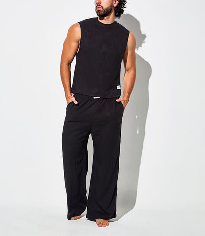 Pantalon pants hombre relajado negro - Hombre luciendo conjunto negro de camiseta sin mangas y pantalón tipo pijama, estilo cómodo y relajado.